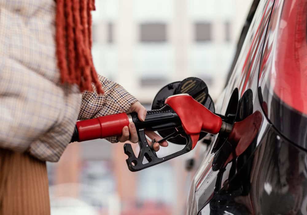 A woman refueling her gasoline red car 
