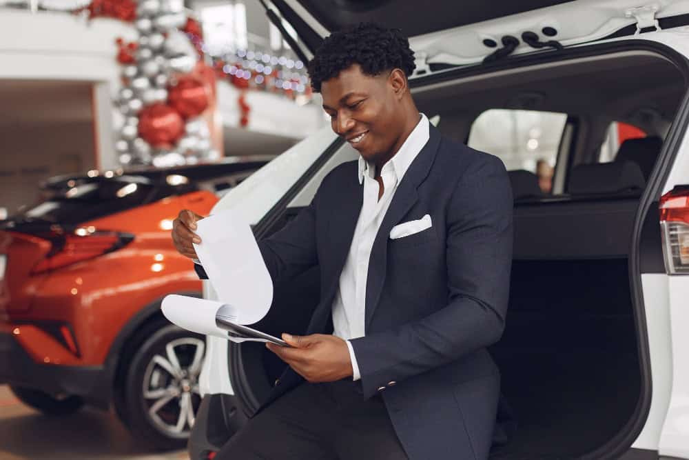 black man going through the paperwork at a dealership