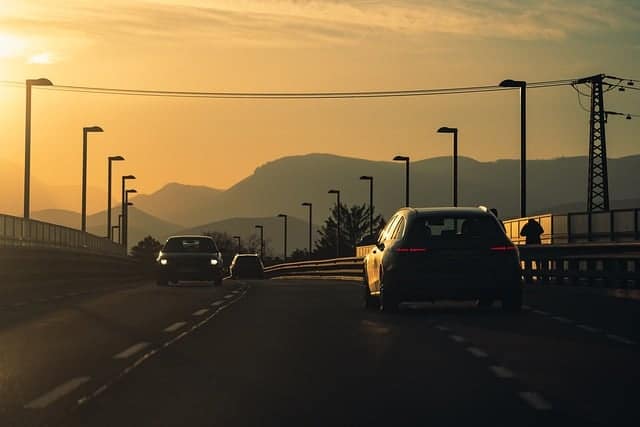 driving in the evening on a 2 lanes road bridge illustrating the cars plying the road have a valid vehicle insurance license